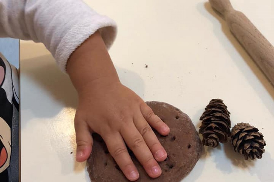 Manipolazione di pasta di pane al cacao, con utilizzo di legnetti e pigne